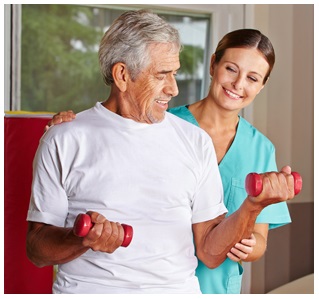 Female Physical Therapist standing behind an elderly man that is lifting small weights